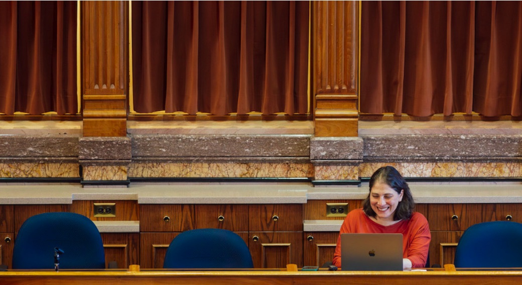 Laura Belin working at a laptop on the press bench in the Iowa Capitol